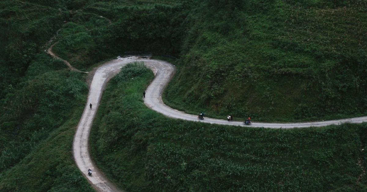 A narrow road winding through green hills seen from above