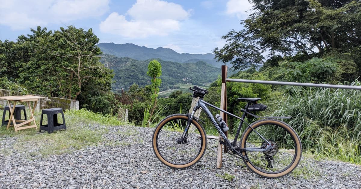 A gravel bike parked on a stony track with mountains behind