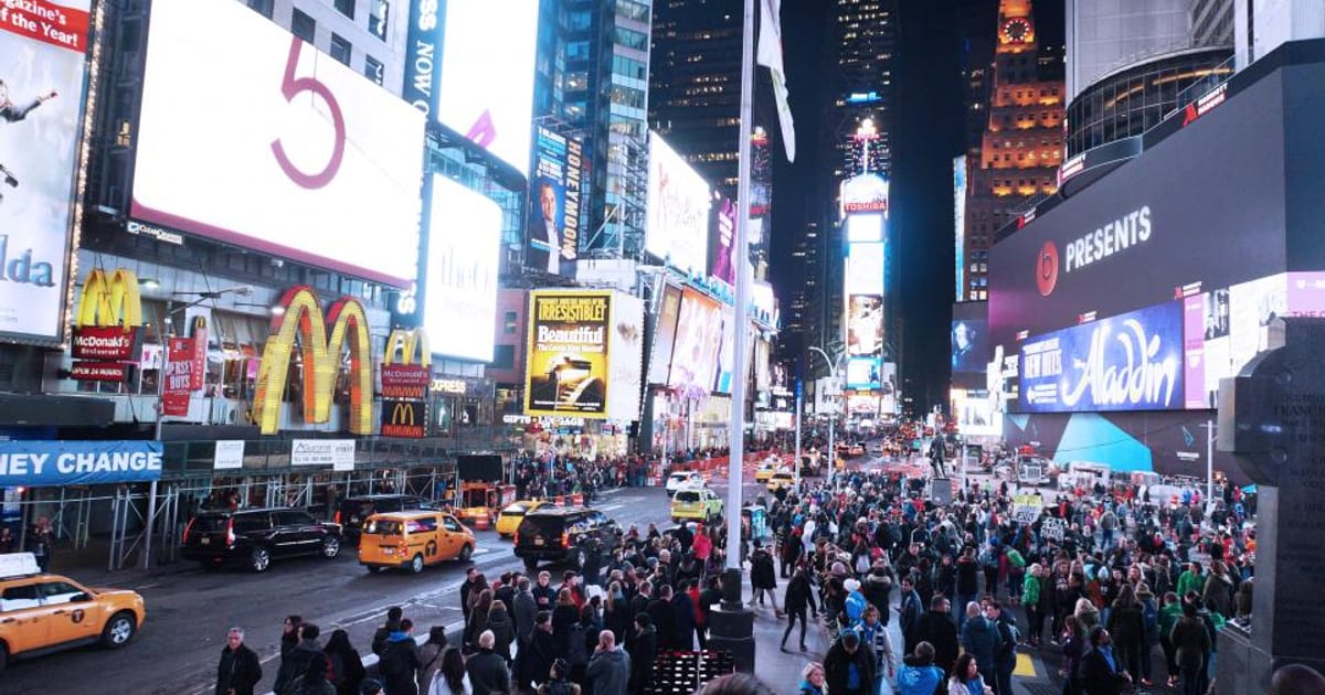 A crowded city street lined with large illuminated billboards
